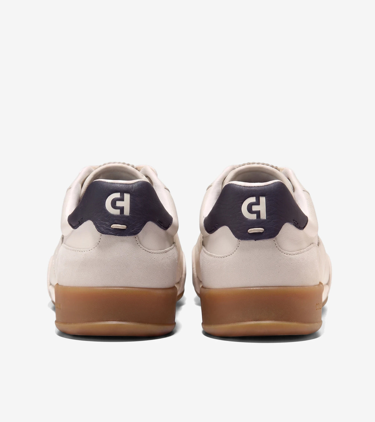 Rear view of two GRANDPRO TURF 2.0 sneakers in ivory and silver birch, with dark blue heel tabs and brown gum soles.