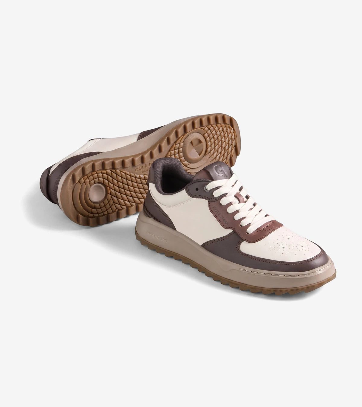 Pair of men's Cole Haan GP Crossover Golf shoes in ivory and madeira with white laces, displayed on a studio background.