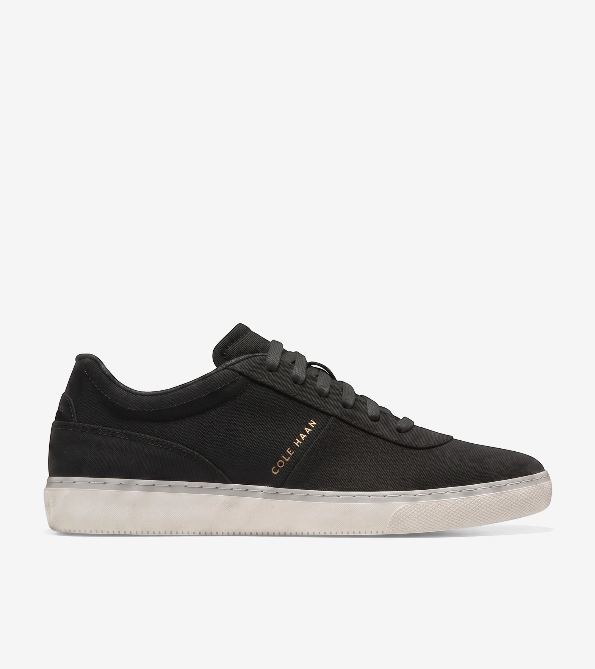 Black Cole Haan Men's GrandPrø Packwell Sneaker with a contrasting white sole and dark grey laces, presented in a clean side
